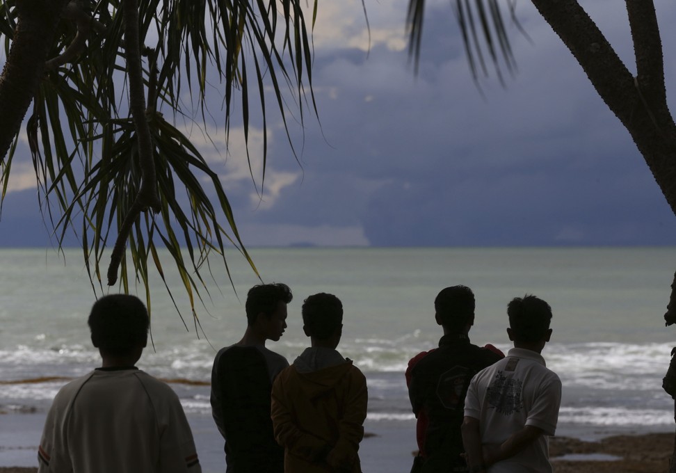 People watch as Mount Krakatoa, left, and Anak Krakatoa, right, are seen off the coast of Carita beach in Indonesia. Photo: AP