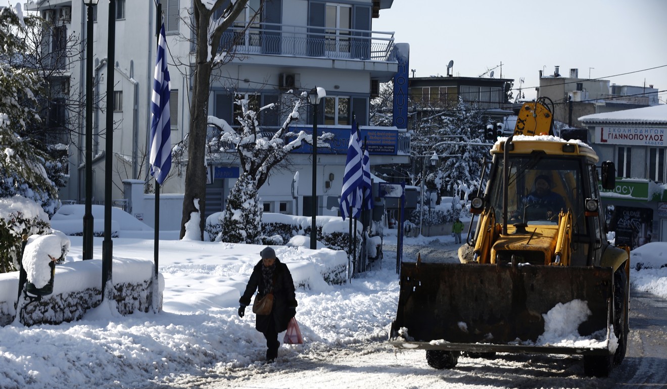 A bulldozer cleans up snow from a road in northern Athens. Photo: EPA