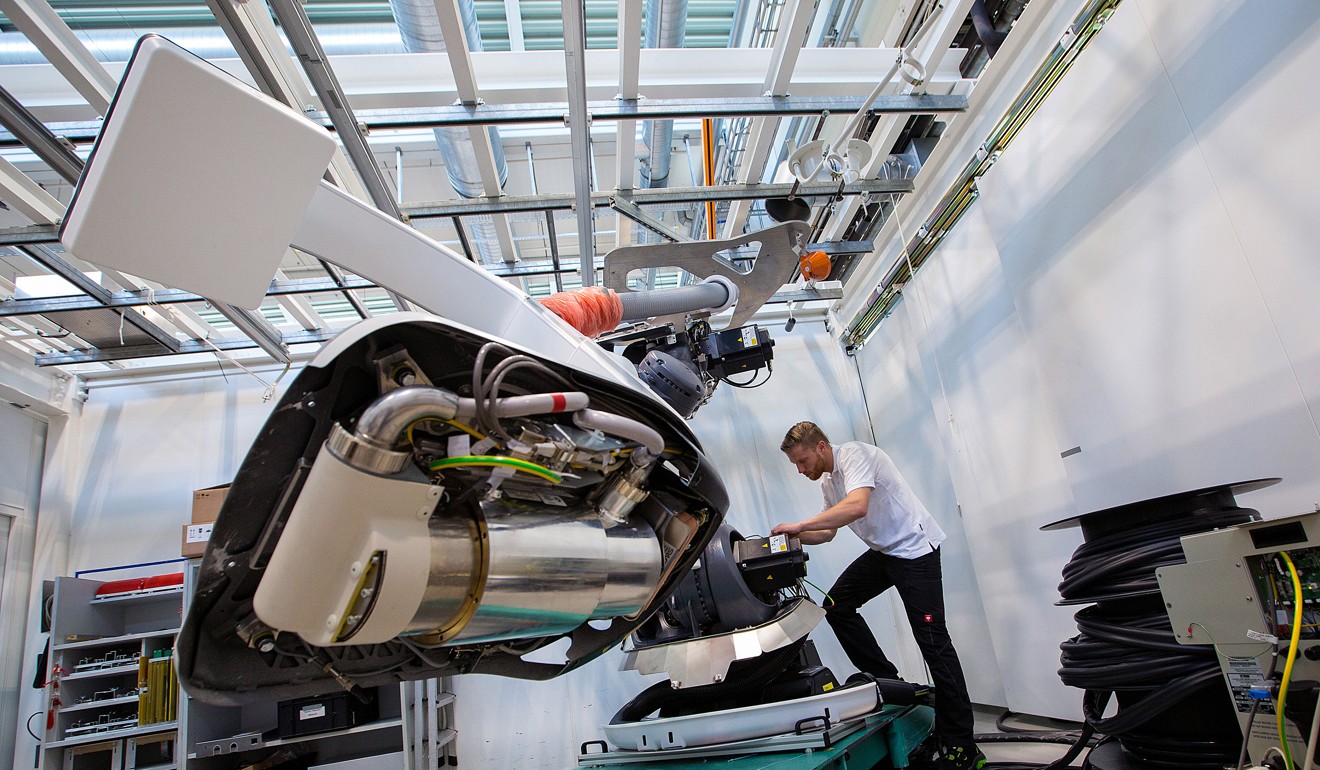 An employee uses a robotic arm while working on a Siemens angiography system on the assembly line at the Siemens AG Healthineers factory in Forchheim, Germany, in July 2017. A survey of global manufacturing and services output showed that growth slowed to its weakest level in January since September 2016. Photo: Bloomberg
