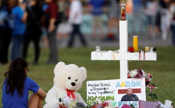 A mourner sits by a cross at a memorial for victims of the shooting at Marjory Stoneman Douglas High School in Parkland, Florida, US. Photo: Reuters