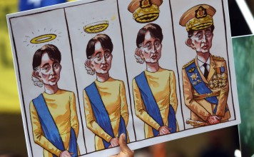 Posters with cartoons featuring Myanmar’s State Counsellor Aung San Suu Kyi are held up at a protest in Sydney on March 17, 2018. Photo: AFP