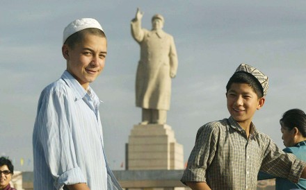 Uygur boys walk past a looming statue of Mao Zedong facing Renmin Square in Kashgar, Xinjiang. Photo: AFP