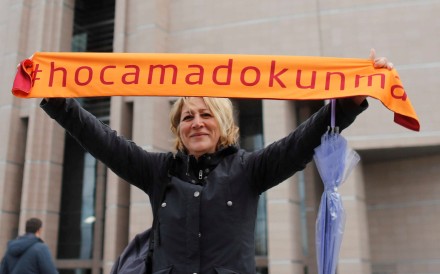 A demonstrator holds a scarf reading “Do not touch my academics” in front of the Justice Palace. Photo: Reuters