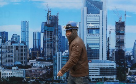 A Chinese migrant worker walks past a poster showing the planned skyline of Beijing. Photo: EPA