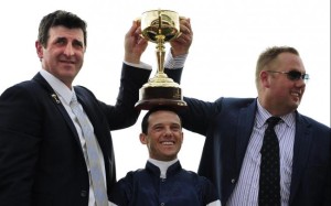 Trainer Robert Hickmott, Hong Kong-based jockey Brett Prebble and owner Nick Williams celebrate with the Melbourne Cup after 19-1 shot Green Moon's sensational victory at Flemington. Photo: EPA