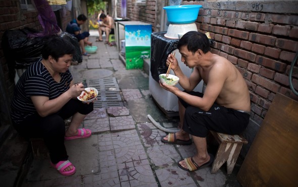 People eat dinner outside their rooms on a street in a migrant village on the outskirts of Beijing. Photo: AFP People eat dinner outside their rooms on a street in a migrant village on the outskirts of Beijing. Photo: AFP