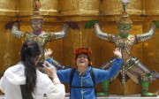 A Chinese tourist strikes a similar pose to statues at the Grand Palace in Bangkok. Photo: Reuters