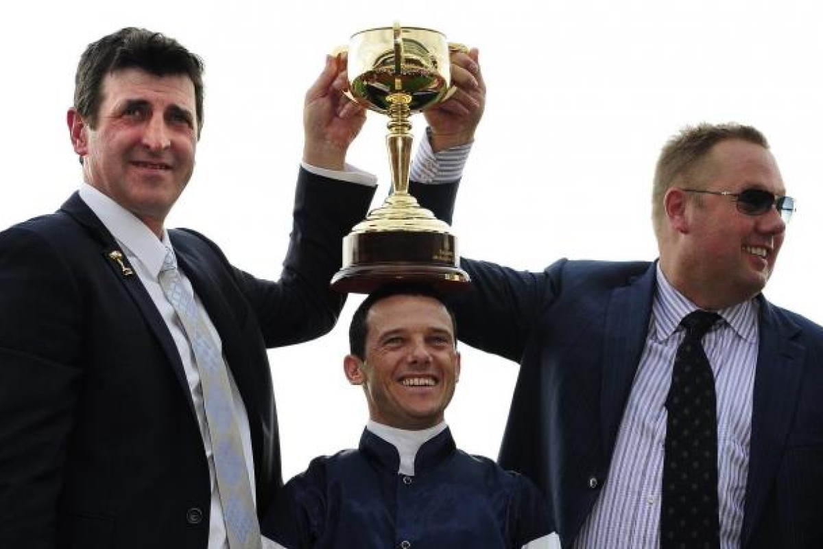 Trainer Robert Hickmott, Hong Kong-based jockey Brett Prebble and owner Nick Williams celebrate with the Melbourne Cup after 19-1 shot Green Moon's sensational victory at Flemington. Photo: EPA