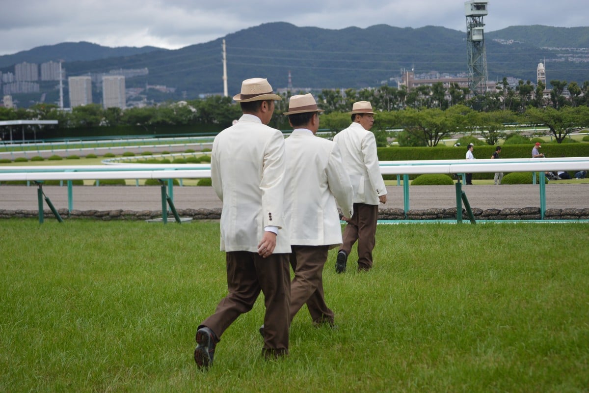 The stewards head out before the Takarazuka Kinen, led by the starter. 